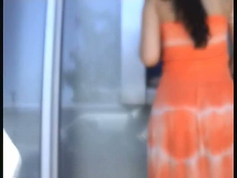 Amateur upskirt video shows a girl in a seductive orange dress.