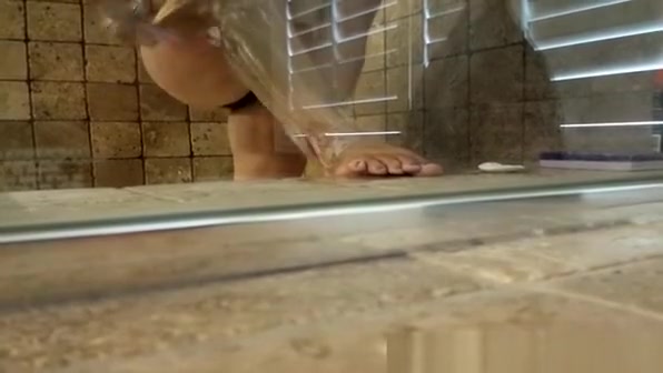 Hairy woman shaving legs in shower