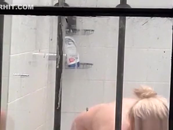 Blonde woman brushes her teeth in the shower