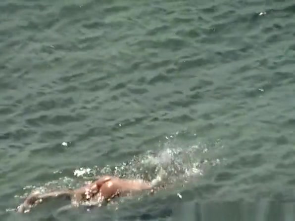 Blonde nudist woman enters the water
