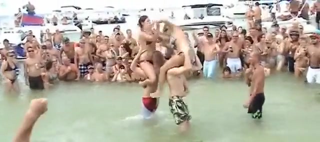 Sexy beach girls fighting each other from the shoulders of their boyfriends
