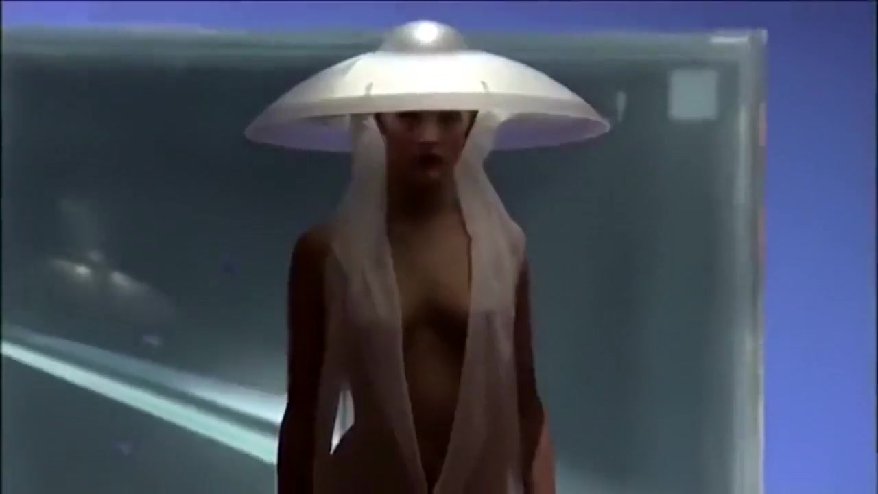 Seductive fashion model in a weird hat walks down the catwalk in the nude
