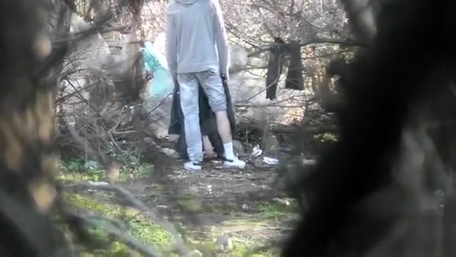 Caring boyfriend covers up girl peeing in the shrub