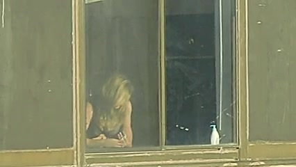 Big tits girl getting dressed by the window