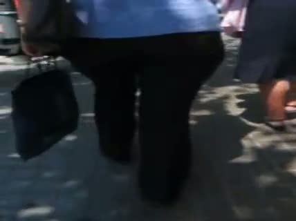 A hefty xxxl woman in a street candid video walks in tight black jeans